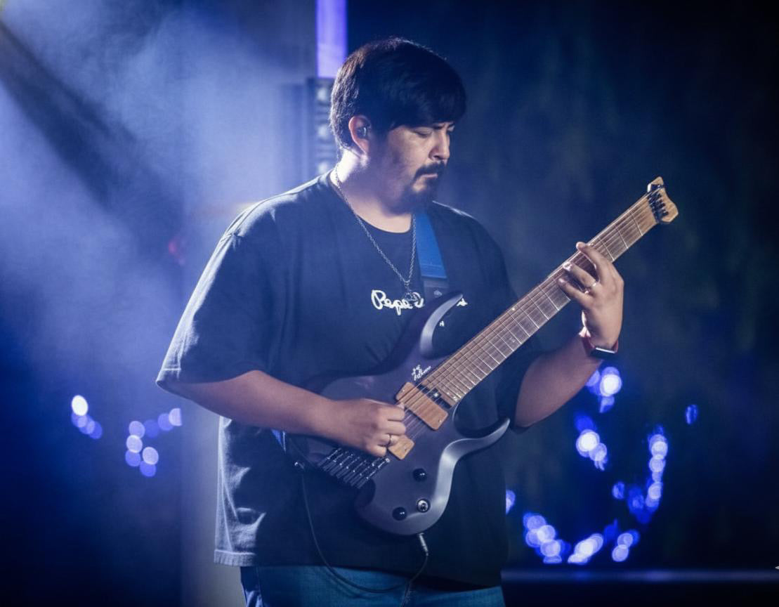 YitanPro performing live with an extended-range guitar under blue stage lighting