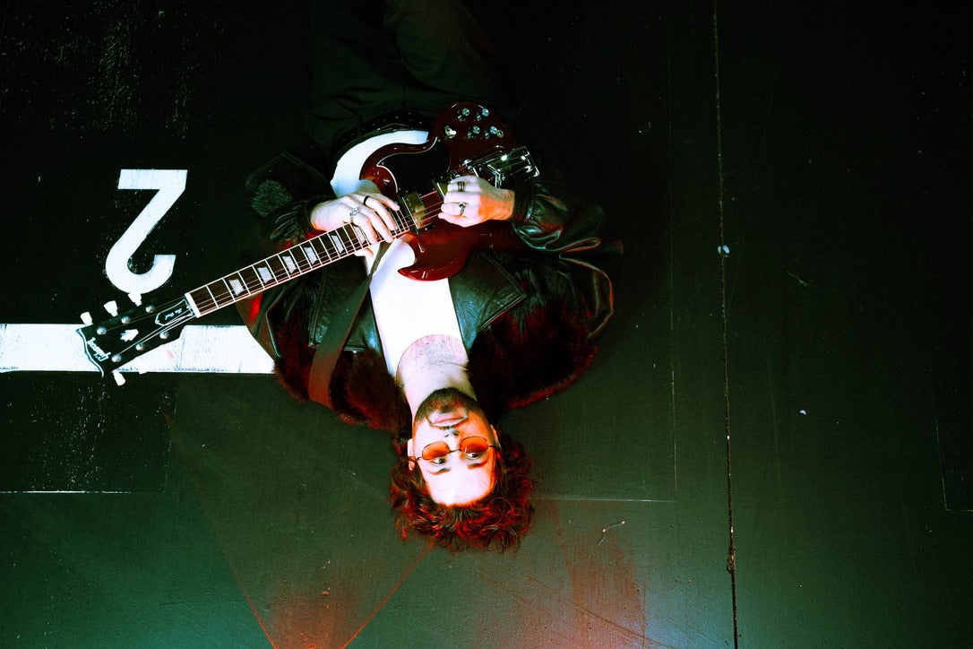 D. LATORRE sentado junto a una motocicleta roja y una Gibson SG