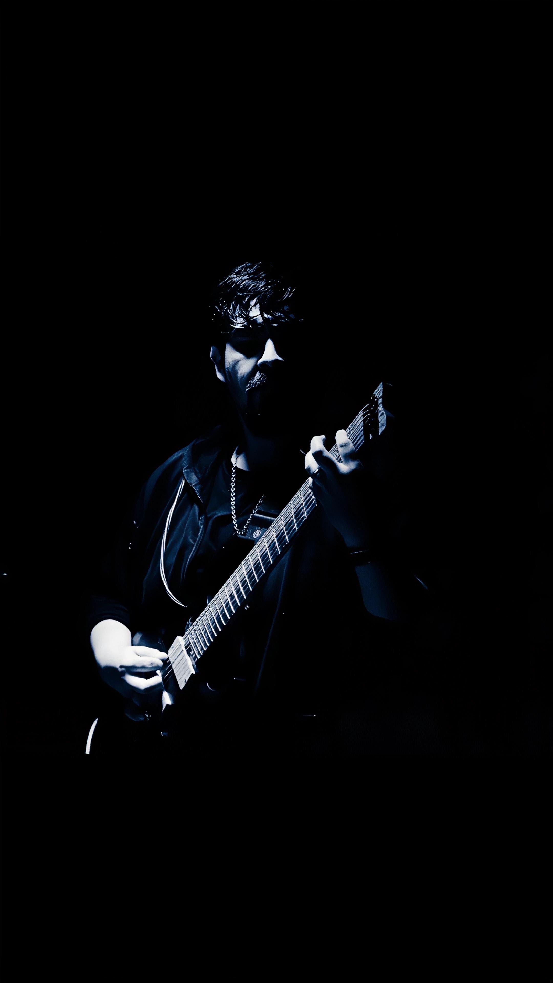 YitanPro holding his guitar in a dark blue portrait