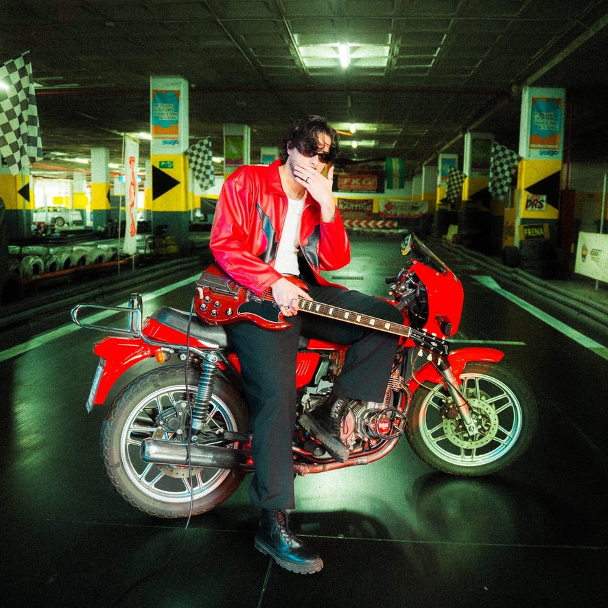 D. LATORRE with a Gibson SG beside a red motorcycle