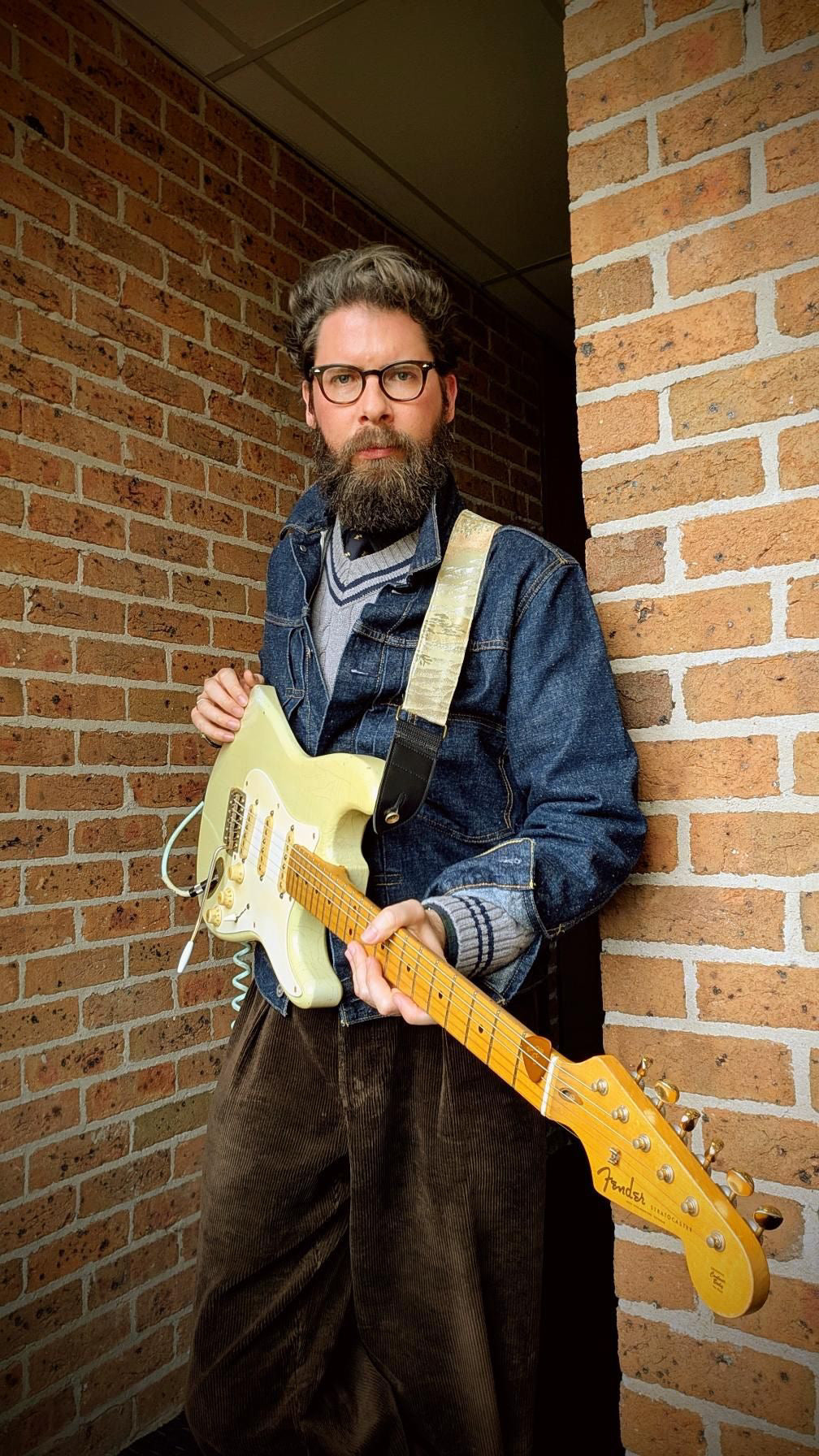 Zane in Australia playing an electric guitar with a white-and-silver Obi Guitar Factory strap